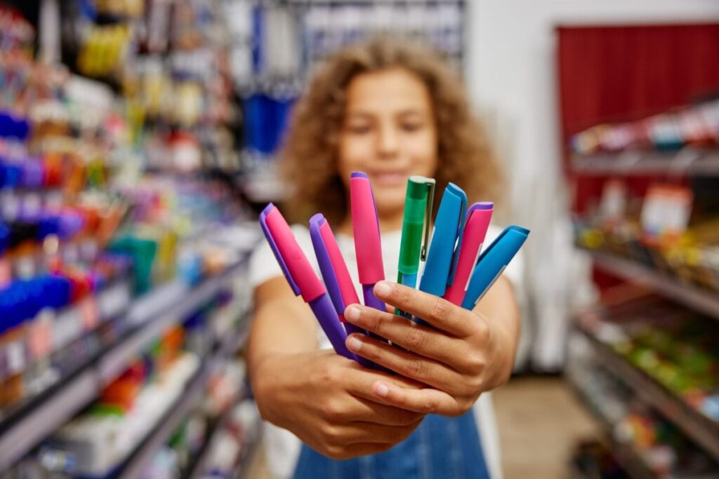 Copil care ține în mână niște creioane colorate