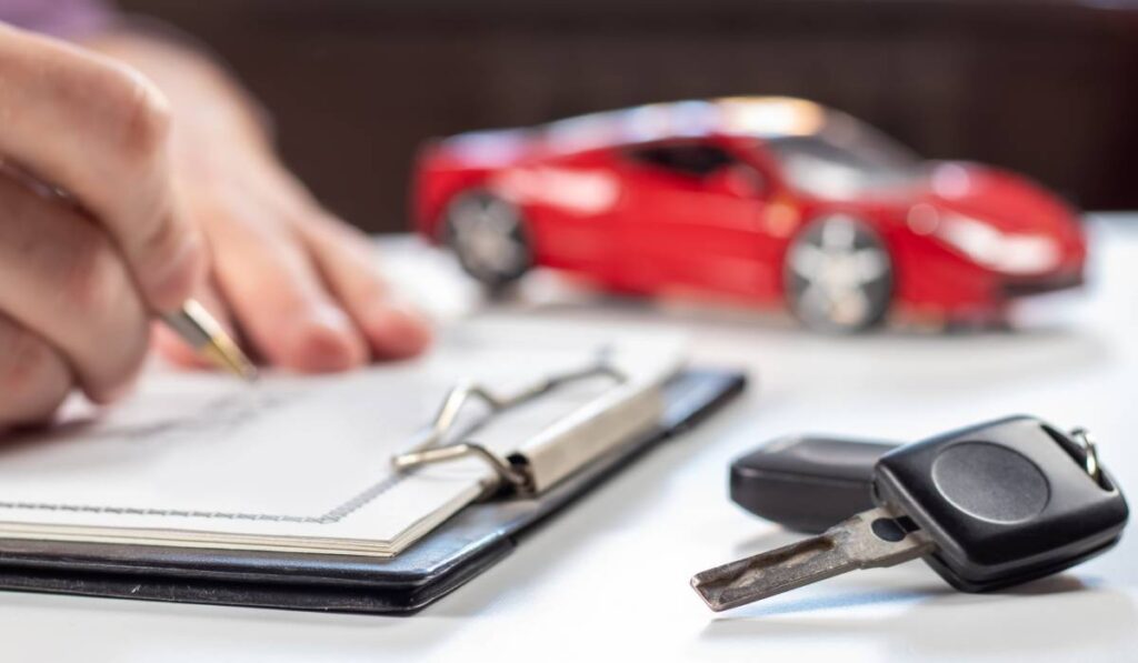 Un bărbat care completează actele pentru vânzarea unei mașini, pe masă sunt și cheile autoturismului