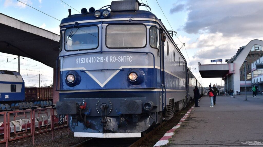 Un tren de călători al CFR vechi, albastru este pe șine într-o stație