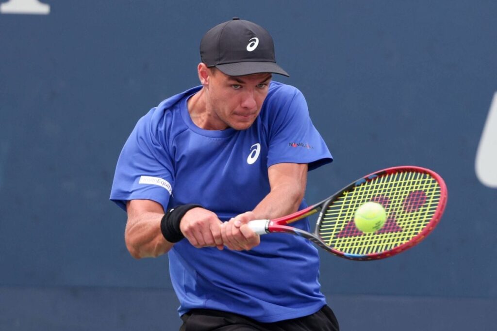 Kamil Majchrzak, cu o șapcă neagră pe cap și în tricou albastru, returnează o minge în timpul unui meci de la US Open, august 2025