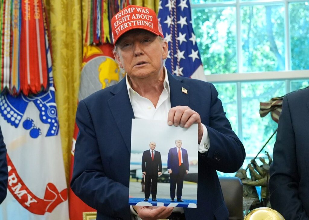 Președintele Donald Trump ține o fotografie cu el și președintele rus Vladimir Putin în timpul unei declarații în Biroul Oval al Casei Albe, vineri, 22 august 2025, la Washington.