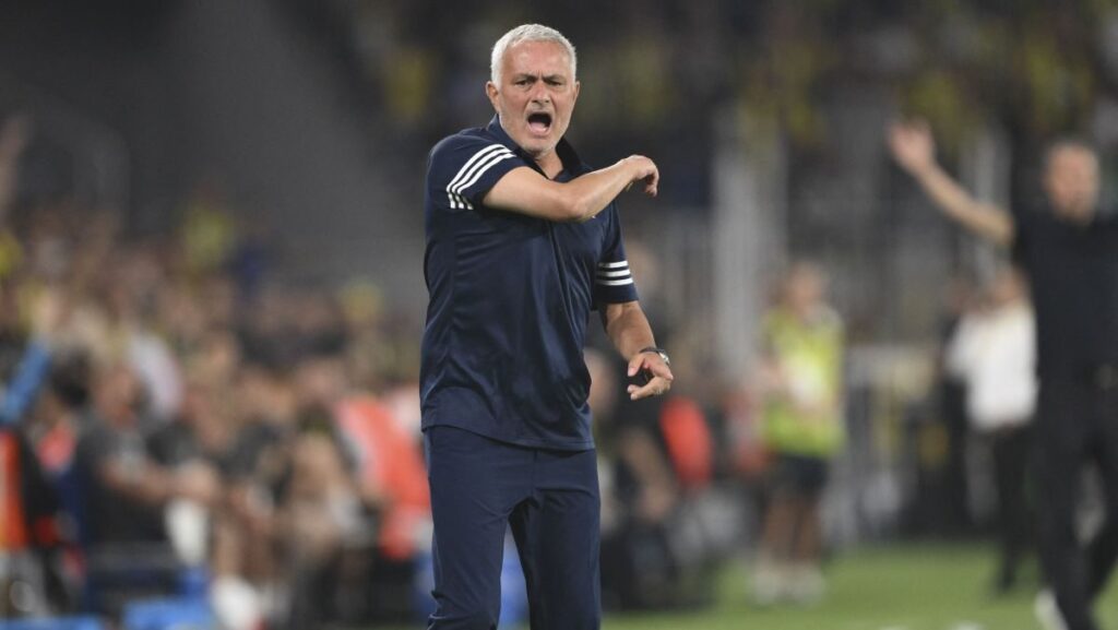 Jose Mournho, înbrăcat într-un tricou negru cu insrții albe, gesticulează cu mâna dreaptă, în timp ce se răstește la jucători de pe marginea terenului, august 2025