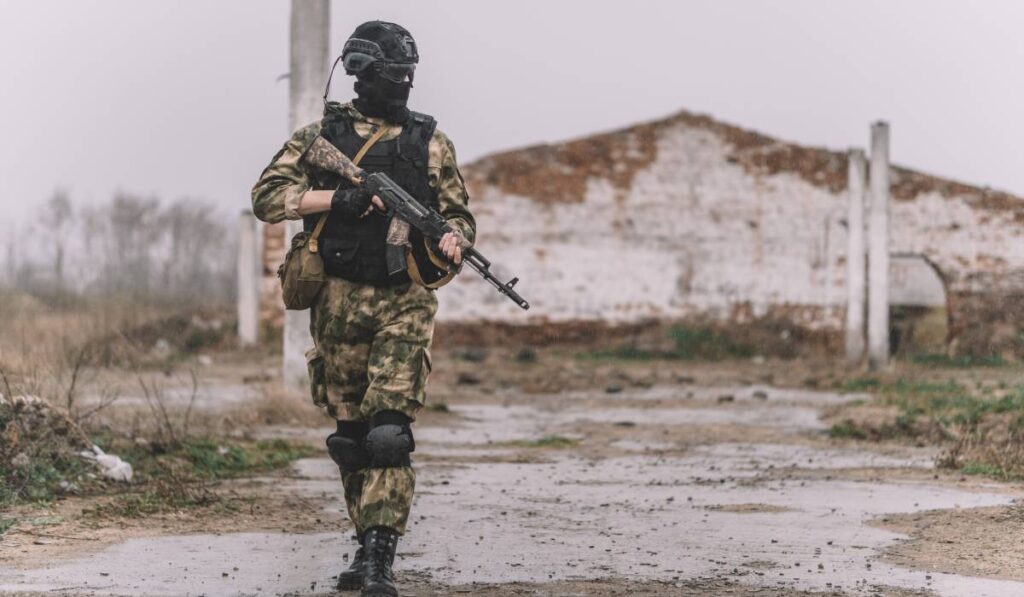 Un soldat îmbrăcat în costum de camuflaj cu o mitralieră în mână