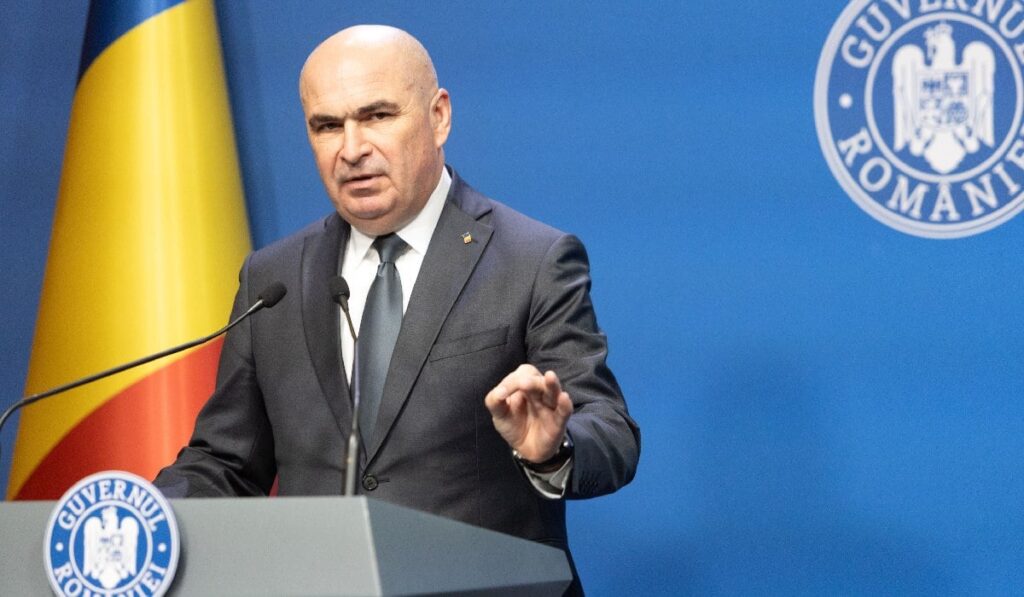 Premierul Ilie Bolojan sustine o conferinta de presa in cadrul careia prezinta pachetul de masuri privind reforma administraţiei publice locale,vineri, 18 iulie 2025, in Bucuresti. In stânga se vede steagul României
