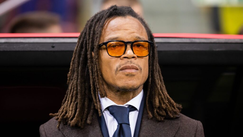 Imagine cu Edgar Davids. Poartă o jachetă închisă la culoare, o cămașă albă și o cravată albastru închis