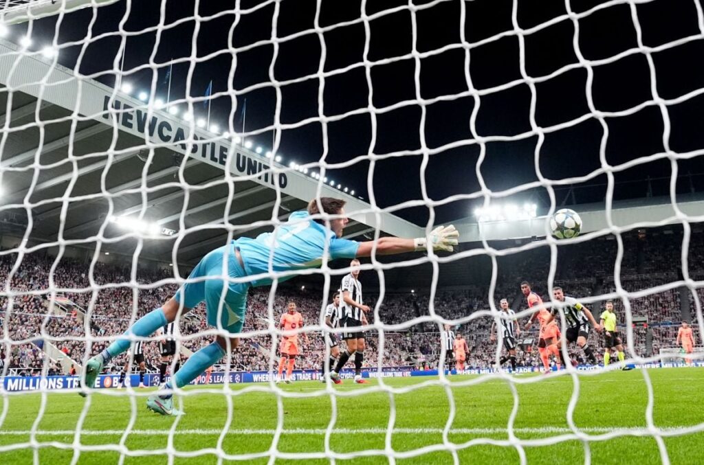 Marcus Rashford, în echipament portocaliu, trimite minge în poartă, cu tot efortul portarului de la Newcastle de a respinge, 18 septembrie 2025