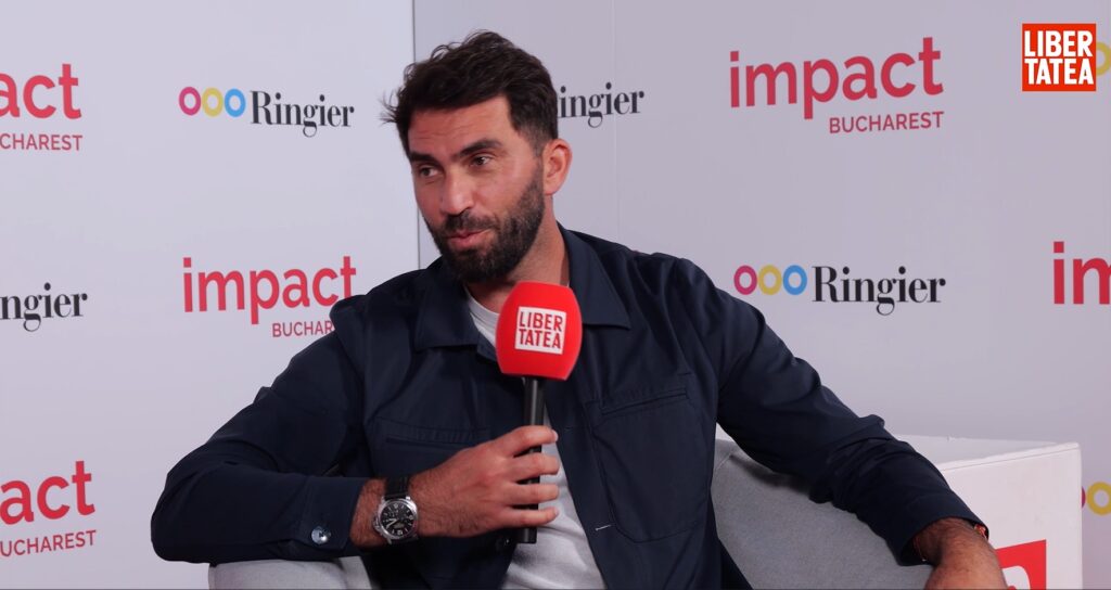 Horia Tecău, interviu pentru Libertatea la Impact Bucharest 2025. Horia Tecau, in geaca neagra si tricou gri, tine in mana un microfon cu sigla Libertatea