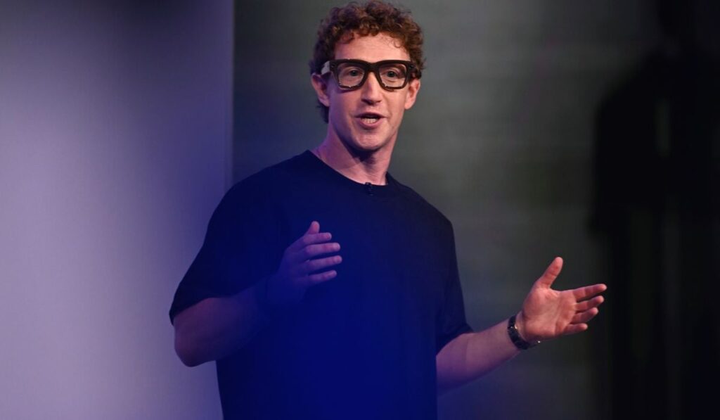 Mark Zuckerberg, purtând noii ochelari Meta cu AI, având un pulover negru, pe un fundal negru, gri și mov.