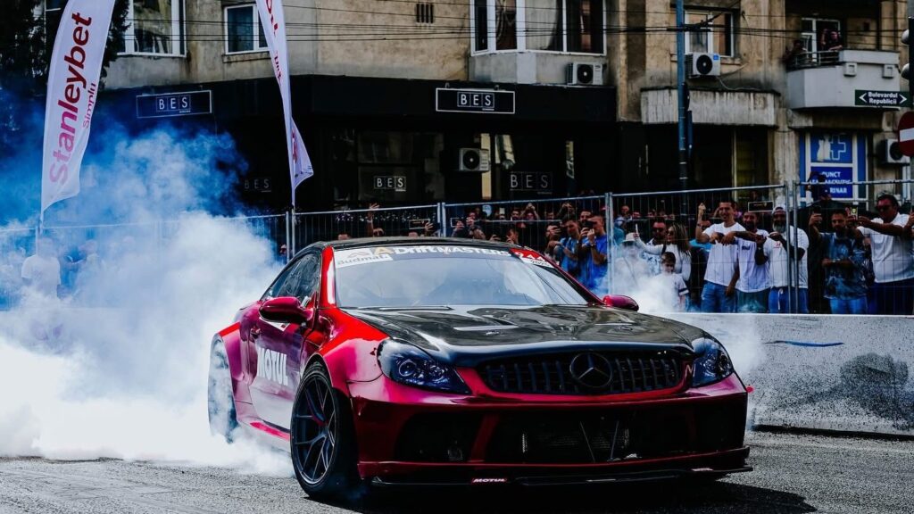 o masina de cursede culoare rosu metalizat cu dungi negre in etapa finală a Campionatului Național de Drift