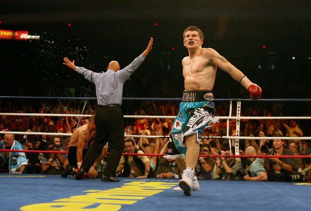 Ricky Hatton se bucură în ring, în timp ce arbitrul face semn că meciul s-a încheiat, privind spre adversarul pugilistului britanic, aflat în genunchi