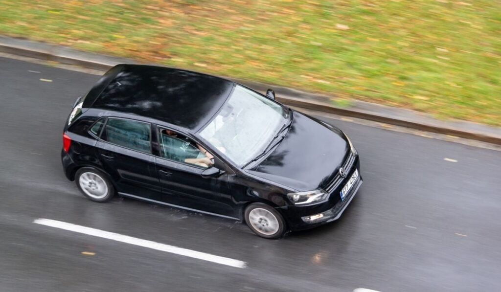 Volkswagen Polo, de culoare neagră, fotografiat din aer, în timp ce merge pe o șosea