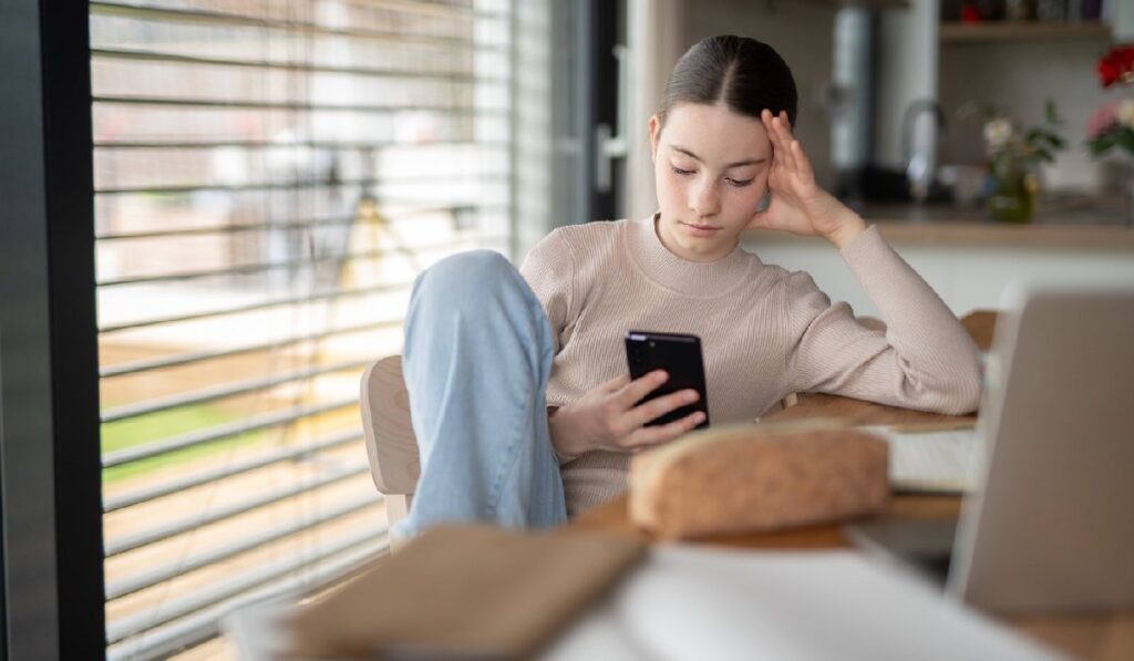 Adolescentă stresată verificându-și telefonul, derulând paginile de social media.