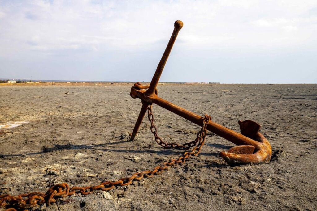 O mcoră ruginită legată de un lanț zace în nisip pe locul în care era lacul Urmia, unul dintre cele mai mari lacuri cu apă sărată din lume, situat în nord-vestul Iranului, februarie 2024