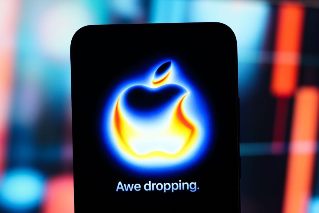 Logo-ul evenimentului iPhone 17 „Awe Dropping” afișat pe ecranul unui smartphone, cu un fundal colorat roșu și albastru.