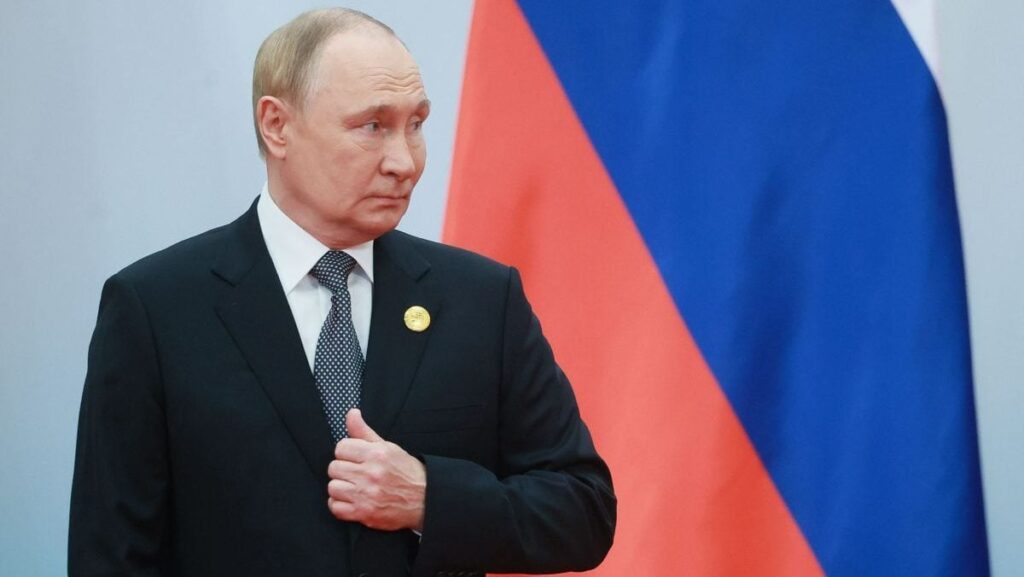 Vladimir Putin, președintele Rusiei, se ține cu mâna de sacou și are în spate steagul țării sale, în timp ce sosește la o reuniune a Consiliului șefilor de stat al SCO (Organizația de Cooperare din Shanghai) la Centrul de Convenții și Expoziții Meijiang, Tianjin, China, 1 septembrie 2025.