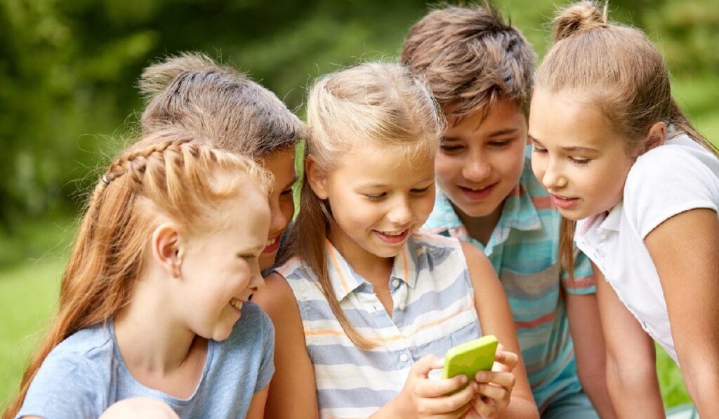Mai mulți copii se uită la un telefon cu carcasă verde