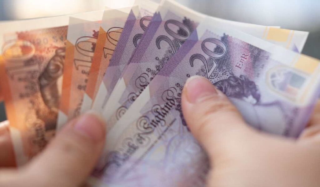 O femeie numără bancnote de 10 și 20 de lire sterline