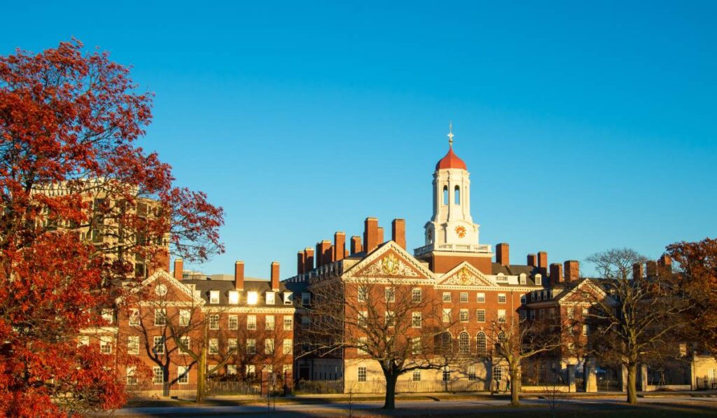 Curtea Universității Harvard toamna, în fundal se vede o clădire din cărămidă, iar în fundal se văd copacii cu frunze maro și roșii