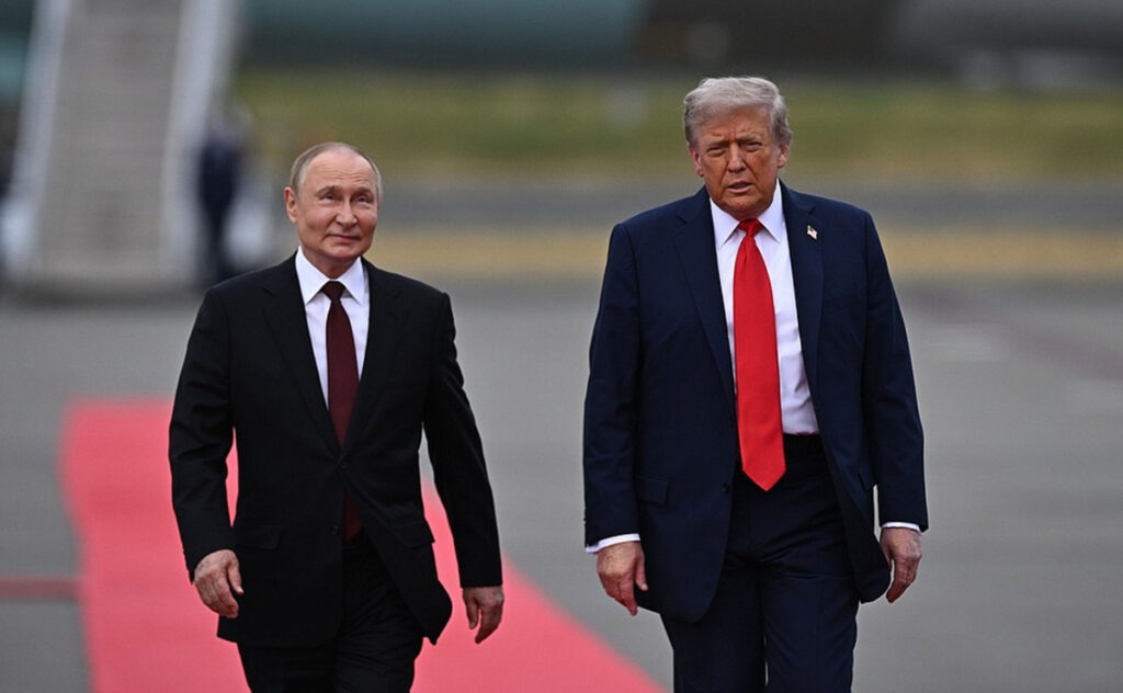 Ce i-a transmis Donald Trump lui Vladimir Putin după testul rachetei Burevestnik Imaginea surprinde doi lideri politici importanți, ambii îmbrăcați în costume închise la culoare, în timp ce pășesc pe o bandă de covor roșu așternută pe o pistă sau platformă exterioară. Bărbatul din stânga poartă un costum negru cu o cravată bordo, în timp ce cel din dreapta este îmbrăcat într-un costum bleumarin cu o cravată roșie aprinsă, ambii având o expresie serioasă pe chip.