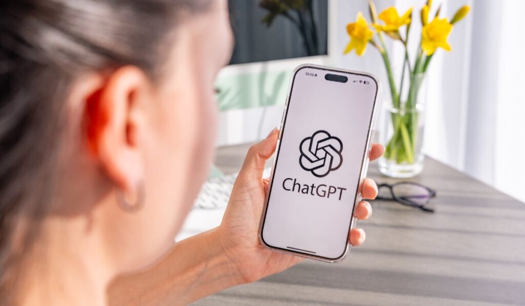 O femeie care ține un telefon în mână pe care este accesat ChatGPT