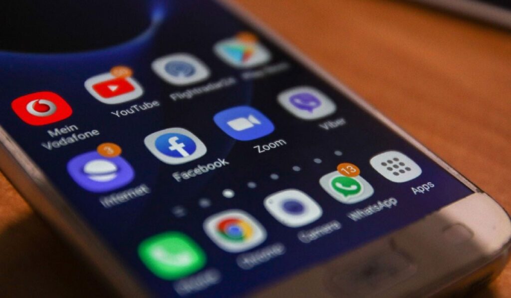 Ecranul aprins al unui smartphone, pe care se văd pictograme ale aplicațiilor