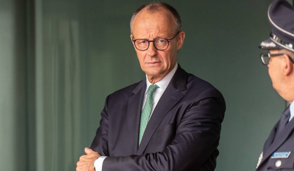 În imagine, Friedrich Merz se uită direct î camera foto. Cancelarul german poartă costum închis la culoare și o cravată verde