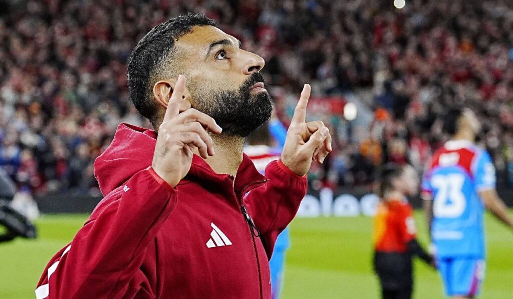 Starul Liverpool-ului, Mohamed Salah, pe terenul de fotbal, privește în sus parcă mulțumind