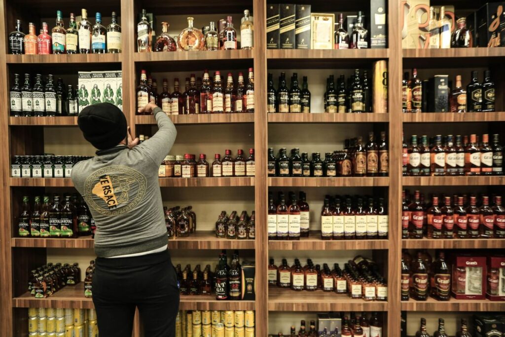 Un bărbat aranjează pe raft băuturi alcoolice, într-un magazin din Bagdad, 24 februarie 2023