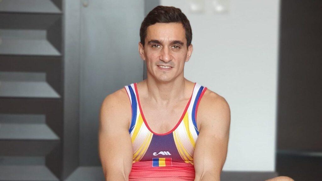 marian dragulescu, in costum de gimnastica, sta relaxat pe covor si zambeste