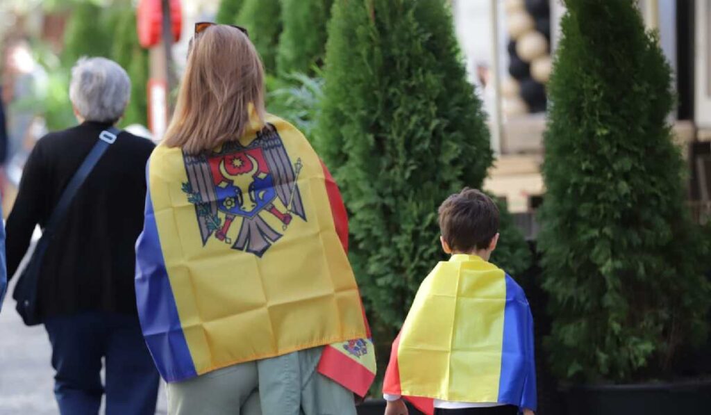 O femeie poartă pe spate steagul Moldovei, în timp ce un copil pe cel al României