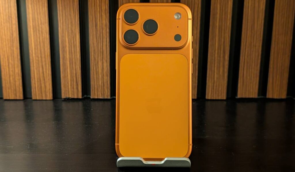 Review iPhone 17 Pro și veșnica întrebare: merită sau nu upgrade-ul? Spatele lui iPhone 17 Pro, de culoare portocalie, pe un fundal de lemn.