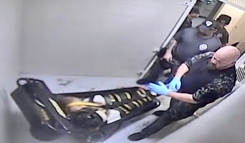 În această imagine din înregistrarea video de supraveghere furnizată de Centrul Corecțional Jefferson City, gardienii îl examinează pe Othel Moore Jr., la Centrul Corecțional Jefferson City din Jefferson City, Missouri, pe 8 decembrie 2023, care, potrivit autopsiei, a murit asfixiat în timpul imobilizării cu WRAP.