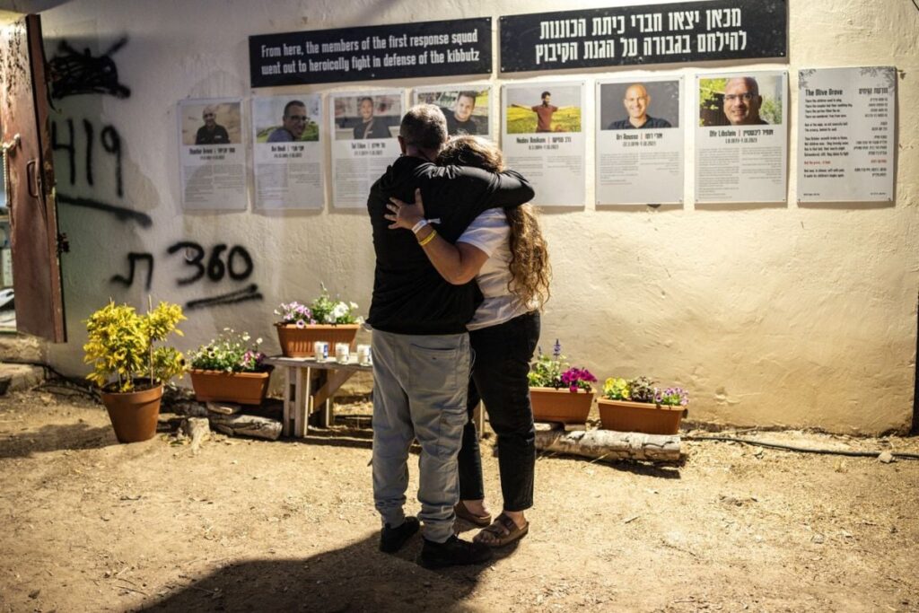 Două persoane se îmbrățișează înaintea unei ceremonii memoriale pentru victimele atacurilor din 7 octombrie 2023, pe terenul Festivalului Nova din Reim, sudul Israelului, 7 octombrie 2025