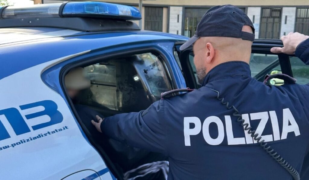 Un tatuaj pe gât a dat de gol un român căutat în toată Europa. Cum l-au prins polițiștii, după o lună de filaj Imaginea arată un ofițer italian stând lângă portiera deschisă a unei mașini de poliție, aparent ajutând pe cineva să urce în vehicul