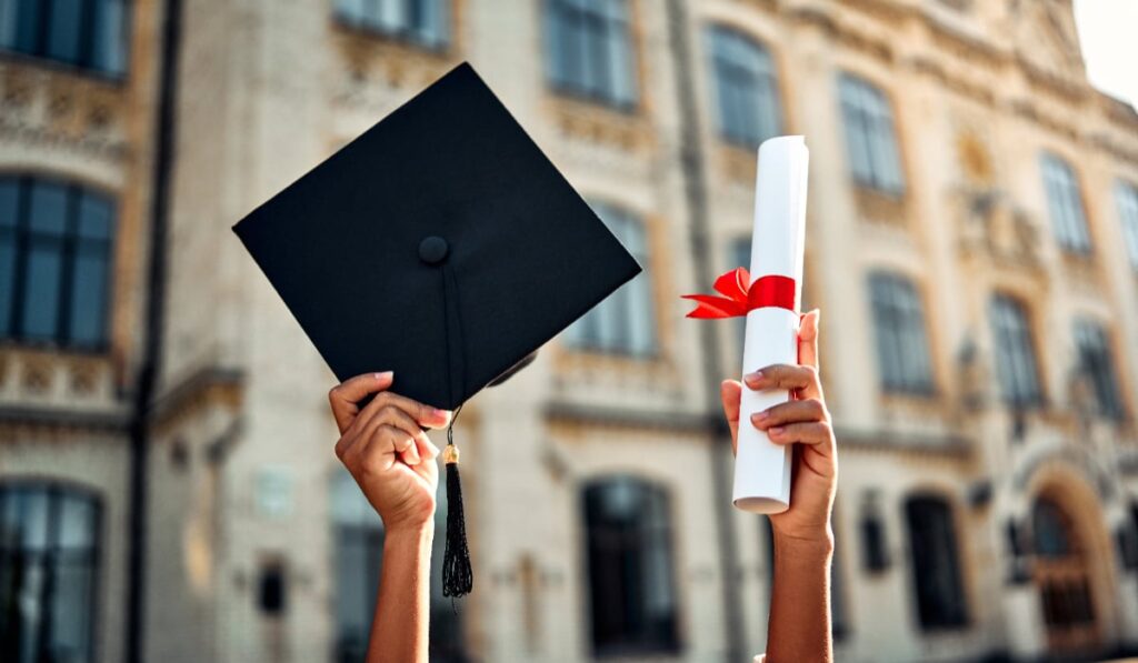 O persoană care ține în mâini toca și diploma de absolvire