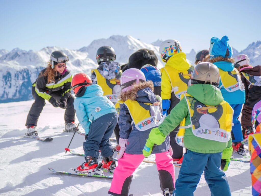 copii pe partie la schi alaturi de un instructor de schi