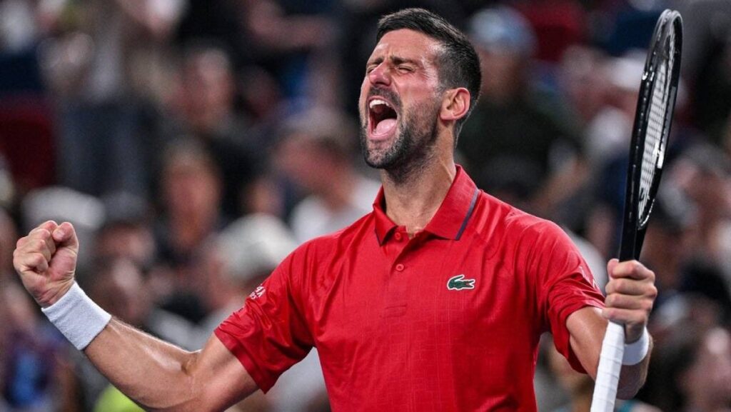 Novak Djokovic, in tricou risu, racheta de tenis in mana stanga si pumnii incleștati, surprins cu gura deschisa, in timp ce urla de fericire după victoria împotriva germanului Yannick Hanfmann în meciul de simplu masculin de la turneul de tenis Shanghai Masters de la Shanghai, pe 5 octombrie 2025.