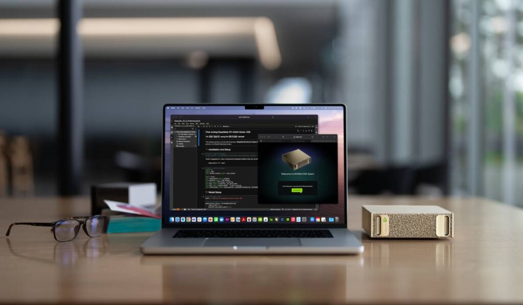 Un MacBook așezat lângă supercalculatorul NVIDIA DGX Spark, pe un bioru de culoarea lemnului.