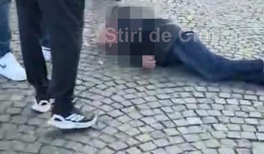 in imagine s evede un barbat intins pe jos pe piatra cubica si alte doua persoane care se uita la el