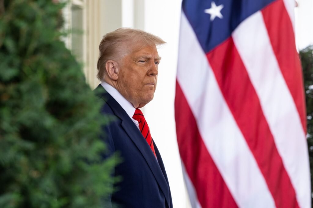 daruri pentru Jenâb-e Âghâ-ye Trump, Ra’is-e Jomhur-e mohtaram Donald Trump, in costum bleumarin si cravata rosie are in fata steagul SUA, iar in spate un copac verde